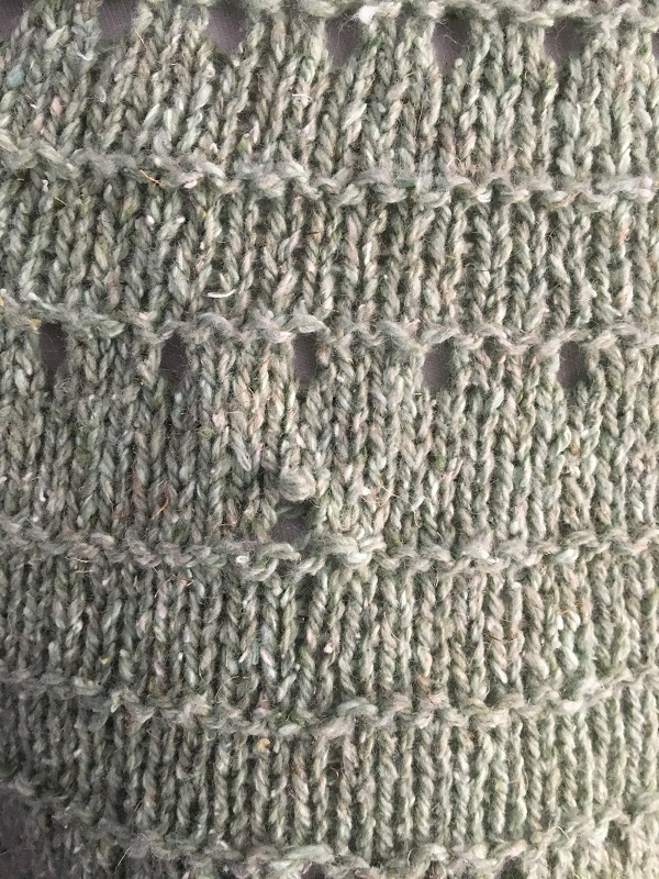 Closeup of the dropped stitch in the Derecho knitted tee.  There is an easy way to fix a dropped stitch.